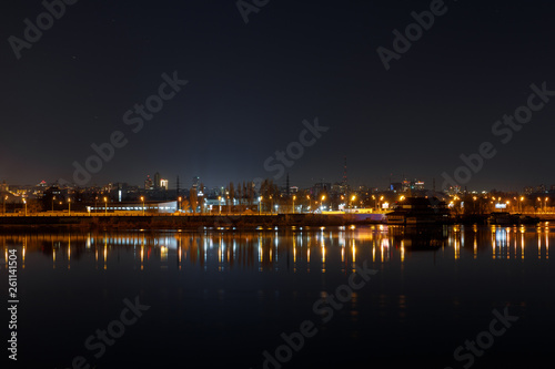 dark cityscape with illuminated buildings and calm river at nigth