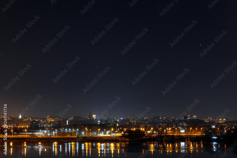 dark and tranquil cityscape with illuminated buildings and reflection on river at night dark and tranquil cityscape with illuminated buildings and reflection on river at night