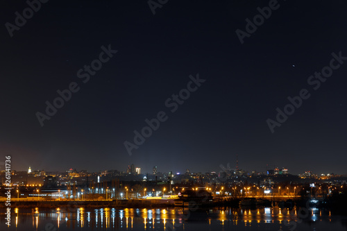 dark and tranquil cityscape with illuminated buildings and reflection on river at night