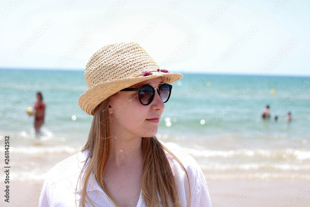 Blonde woman with hat and sunglasses on the sea