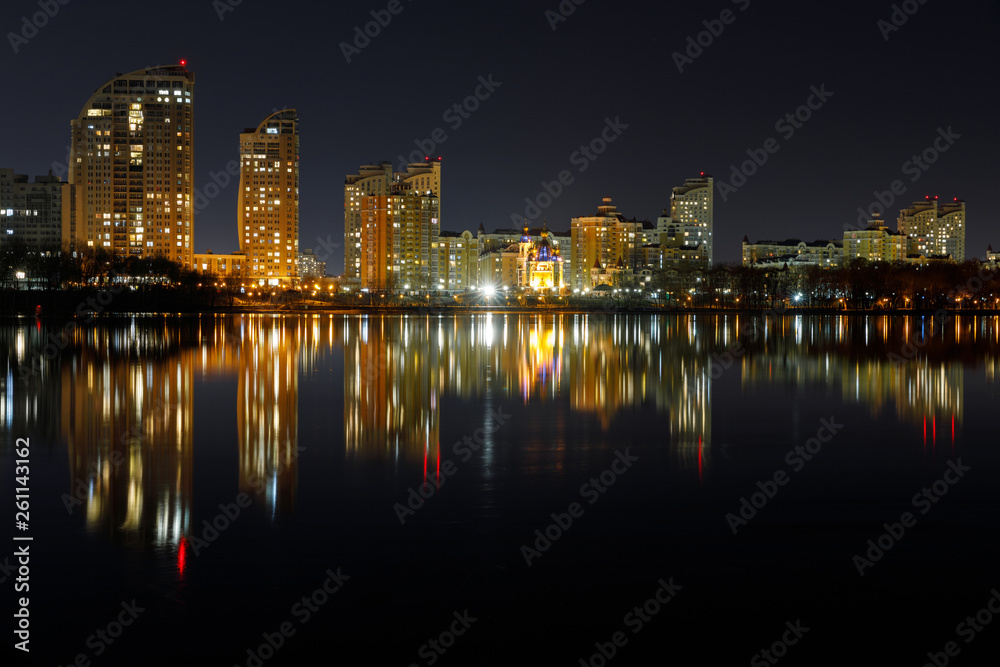 dark cityscape with illuminated buildings with reflection on water at night