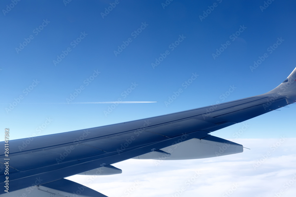 Fototapeta premium view from the window of the aircraft: part of the wing on the background of another aircraft flying in the distance in the sky