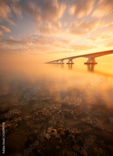 A beautiful sunrise at the Zeeland Bridge. The Zeeland bridge is the longest bridge in Zeeland and is connecting 2 islands. It was a beautiful sunrise, in the foreground you see rocks with oysters. 