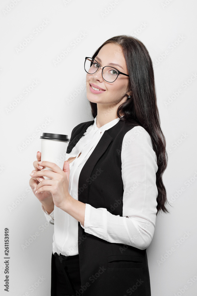 Beautiful young attractive brunette girl with long curly hair wearing glasses against the background of a white wall. Beautiful young attractive brunette girl with long curly hair wearing glasses against the background of a white wall.