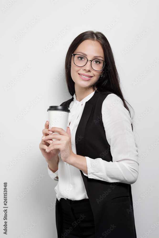 Beautiful young attractive brunette girl with long curly hair wearing glasses against the background of a white wall. Beautiful young attractive brunette girl with long curly hair wearing glasses against the background of a white wall.