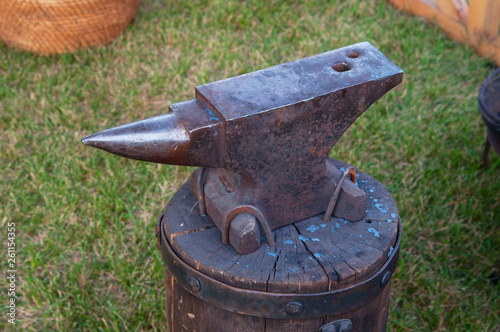 Old big iron blacksmith anvil on a base of an old block of wood in the grass photo