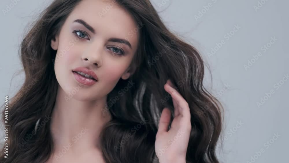 Beautiful woman with long curly brown hair. Fashion model looks to the camera at studio. Beautiful woman with long curly brown hair. Fashion model looks to the camera at studio.