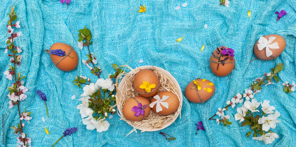 Easter decor, painted eggs on a bright blue background with space for text and spring flowers. Bright preparation of Easter cards. Orthodox and Catholic holiday. family celebration, flat lay