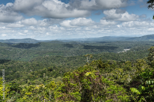 Cairns, Australia - February 18, 2019: Wide view over green Kuranda green Rain Forest with its hills. Blue sky with dense white cloudscape.