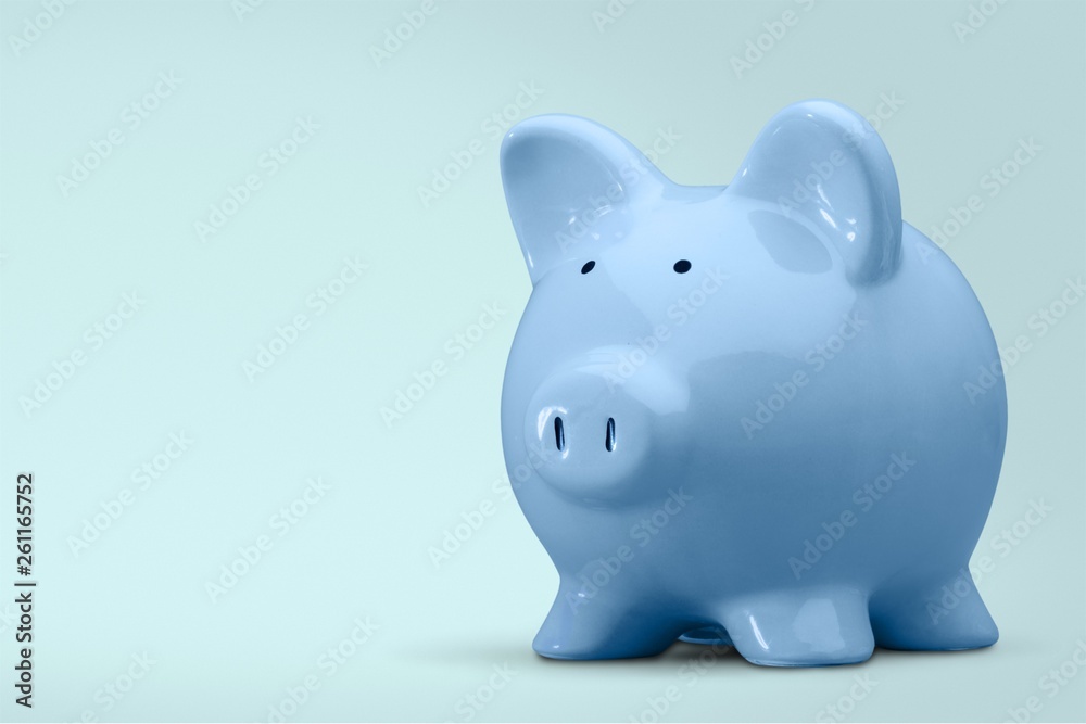 Hand putting coin to piggy bank on blue background