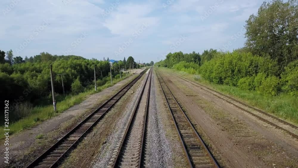 Drone view of four rows of long railways laying between green line of bushes and trees at some suburb area on warm summer sunny day. Drone view of four rows of long railways laying between green line of bushes and trees at some suburb area on warm summer sunny day.