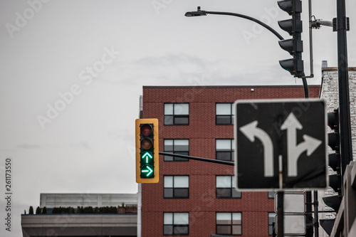 Traffic light abiding by American standards indicating two directions with green light, at a crossroad, with a sign indicating the intersection with distinctive arrows  photo