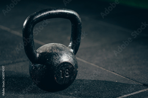 Black heavy kettlebell on gray floor, weightlifting