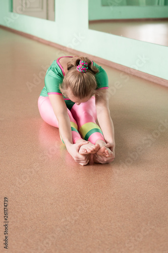 The girl in the hall studies yoga and trains the body stretch