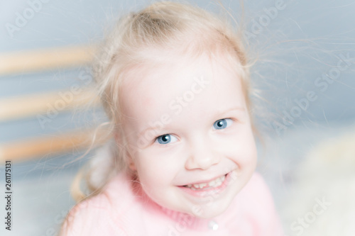 The little girl in the pink sweater is smiling