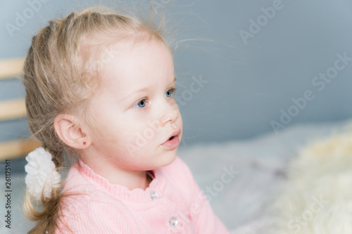 Little girl in a pink sweater looks away