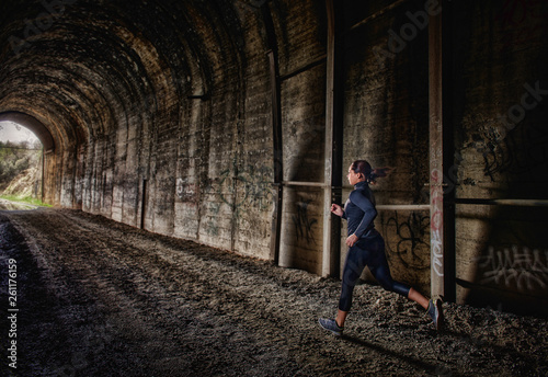 A young woman running through a tunnel as part of her morning fitness routine.