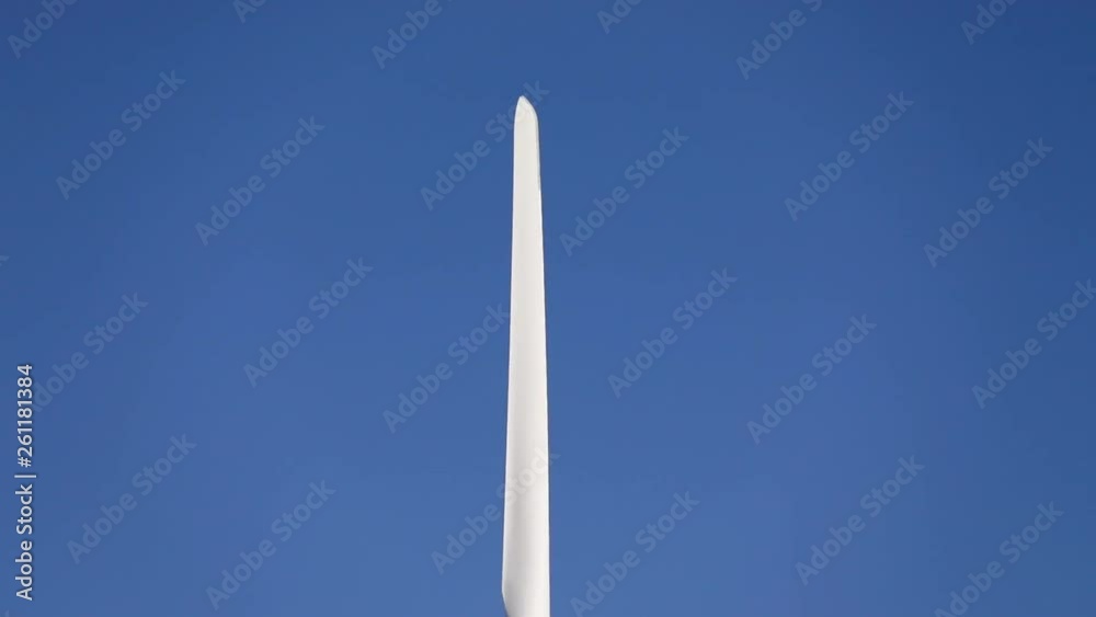 Rotating wings of wind turbine with the clean blue sky in the background. Wind energy equipment producing power from a renewable source. Rotating wings of wind turbine with the clean blue sky in the background. Wind energy equipment producing power from a renewable source.