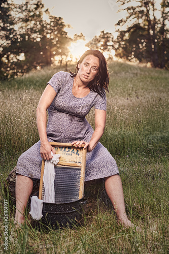 фотографія Country woman in retro scene washing clothes with a washboard outdoors at sunset