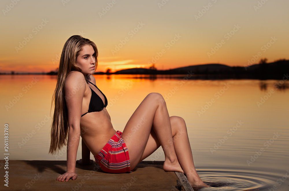 A young woman sitting on a dock of a small lake in Northern California at sunset.