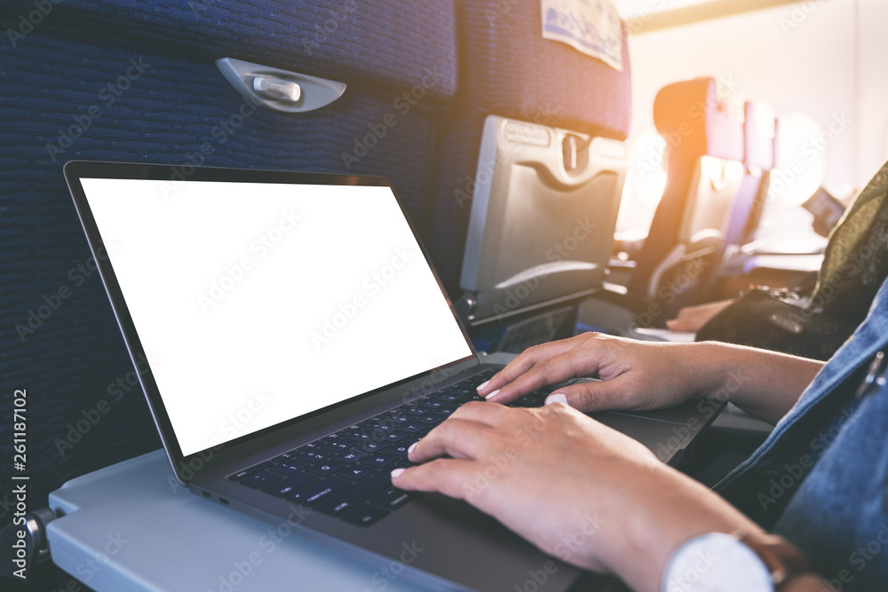 Mockup image of a woman using and typing at laptop computer with blank white desktop screen while sitting in the cabin Mockup image of a woman using and typing at laptop computer with blank white desktop screen while sitting in the cabin