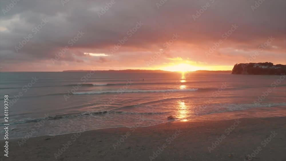 Surfers ride waves during sunrise at Orewa Beach in New Zealand Surfers ride waves during sunrise at Orewa Beach in New Zealand