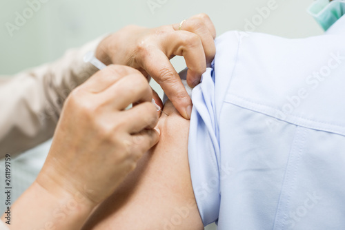 Close up doctor s hand injecting for vaccination in the shoulder woman patient.Vaccine for protection concept