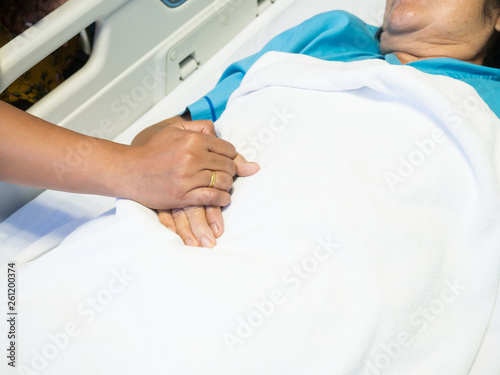Close up hand in hand of mother and daughter on hospital bed.Caregiver and hopeful concept