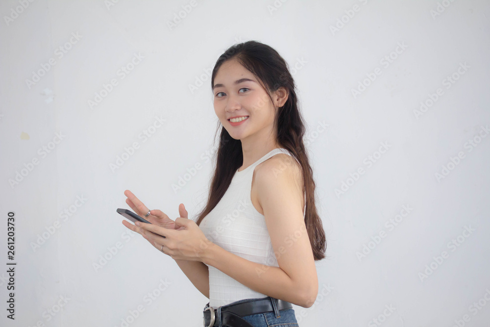 Portrait of thai china adult beautiful girl White shirt blue jeans using her smart phone Portrait of thai china adult beautiful girl White shirt blue jeans using her smart phone