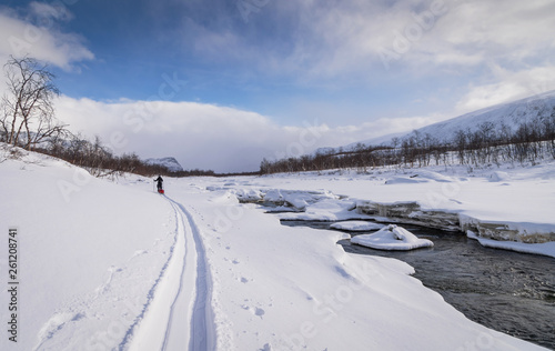 Cross-country skier with sled (pulka)  beside a river in Rapadalen, National Park Sarek. Lapland,  Sweden. © sanderstock