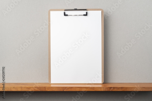 front view of A4 paper with clipboard on bookshelf © voyata