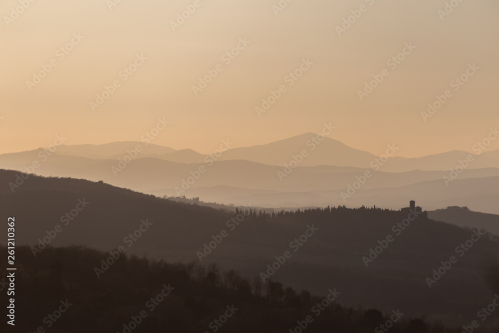 Beautiful view of Tuscany hills at sunset, with mist and warm colors