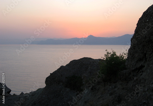Beautiful calm sea at sunset on the background of mountains.