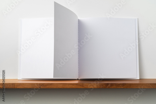 white square notebook on bookshelf and white wall