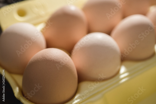 Chicken eggs lie in a yellow plastic tray. photo