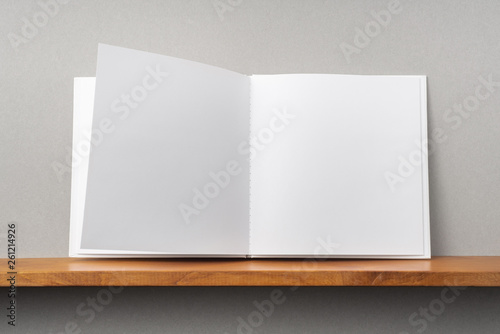 white square notebook on bookshelf and grey wall