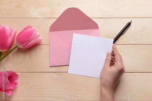 Female hand with invitation on wooden background