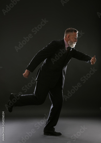 Running mature businessman on dark background © Pixel-Shot