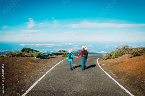 family travel- mother and son walking on road in mountains