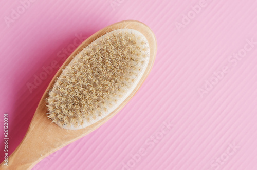 Wooden brush for dry anticellulite massage on pink background. Body care concept photo