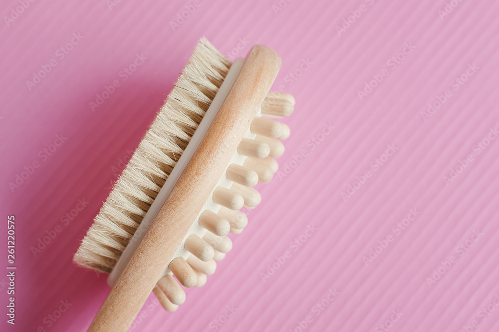 Multipurpose wooden brush for massage on pink background. Dry body massage. Cellulite treatment beauty tool Multipurpose wooden brush for massage on pink background. Dry body massage. Cellulite treatment beauty tool