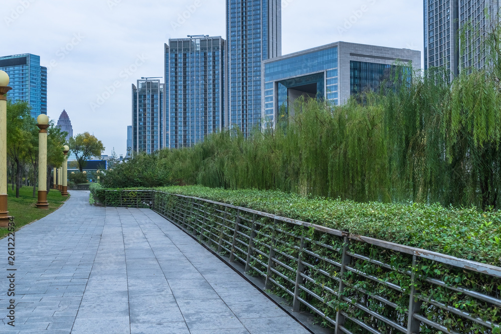 Fototapeta premium park pedestrian walkway and modern skyscrapers, dalian city, china.