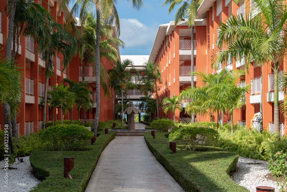Garden hotel with garden paths, palm trees and a green lawn at sunrise.