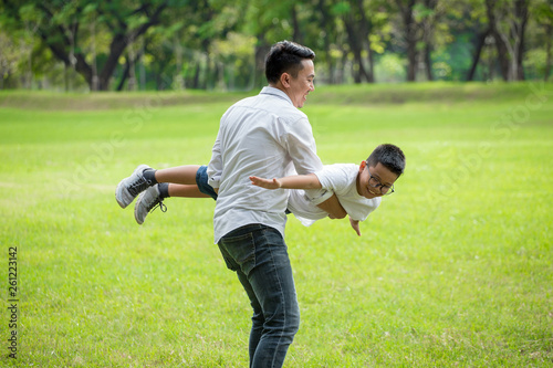 happy asian Family .Father and son having fun playing and stretching out hands  pretending flying  together in the park .dad holding boy  . kid and parents outside.