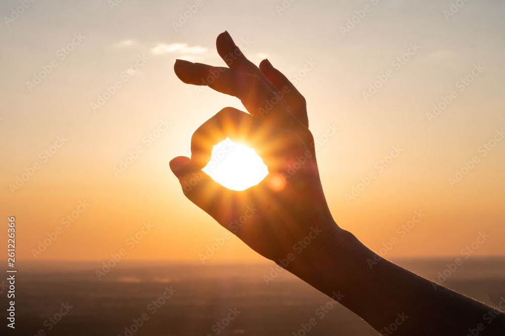 hand sign and sun rays going through hands at sunset - obrazy, fototapety, plakaty 