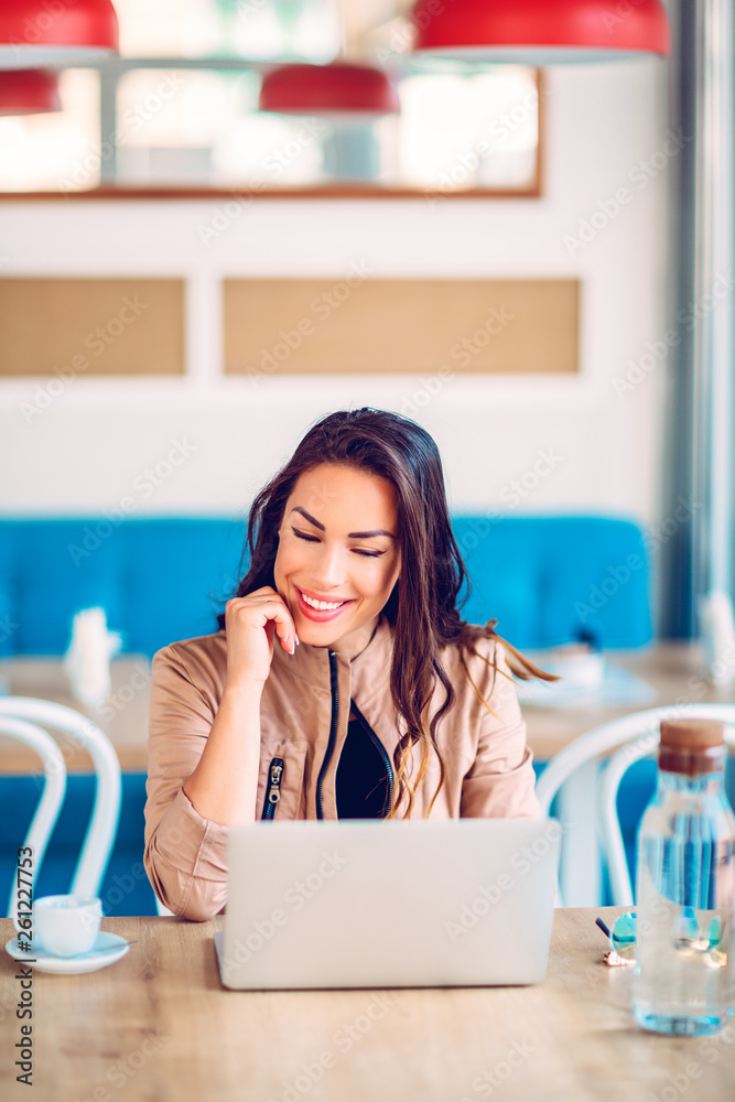 Beautiful brunette using laptop in cafe