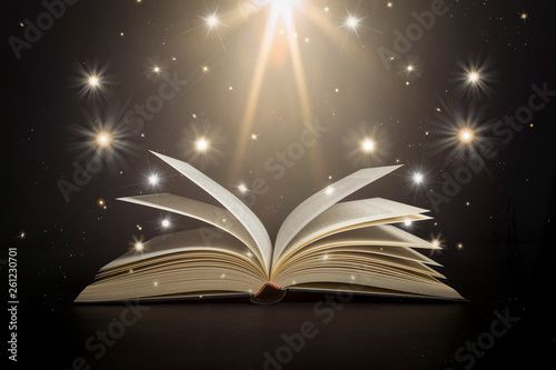 Open book with stars and bright light on a black background as if it were magic