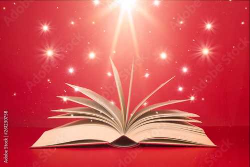 Open book with stars and bright light on a red background as if it were magic