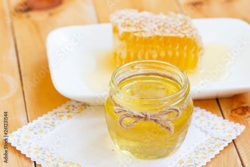 Jar of fresh honey with honey comb. healthy organic natural products. liquid honey and fresh honeycomb on rustic wooden table. Fresh honeycomb on plate on lace linen napkin close-up.
