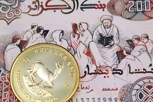 A macro image of a 200 Algerian dinar note with a gold, South African krugerrand
